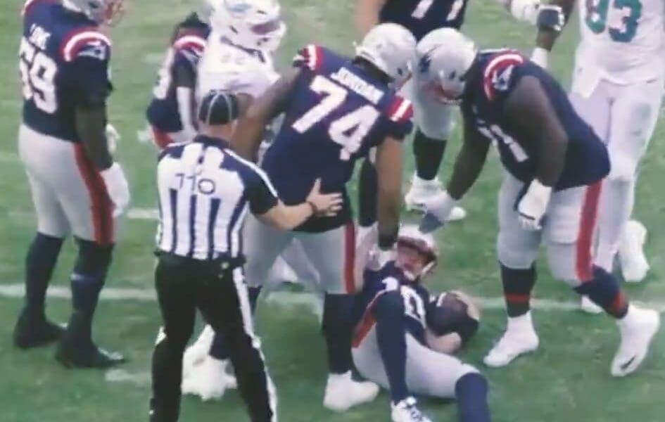 New England Patriots offensive guard Michael Jordan helps up quarterback Drake Maye following a sack.